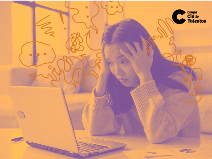 A imagem ilustra o assunto do artigo que é: Ansiedade: como lidar com ela antes da dinâmica de grupo. Está em tom alaranjado, mostrando uma moça oriental, de cabelos escuros e lisos na altura dos ombros, com as mãos na cabeça. Ela olha para o computador e demonstra preocupação. Em volta dela, algumas ilustrações como rabiscos, simbolizando que ela está confusa.