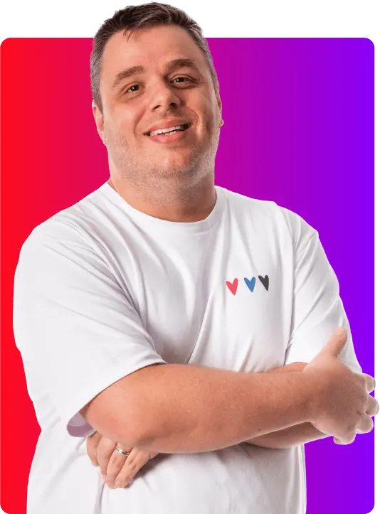 Homem branco com deficiência não visível, colaborador da Globo, branco com cabelo levemente grisalho, vestindo uma camiseta branca com uma pequena estampa de corações, sob um fundo gradiente de roxo e vermelho.